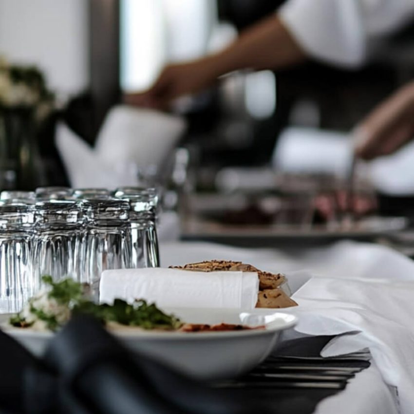 Close-up of an elegant corporate table setting with wine glasses, plates, and formal catering service