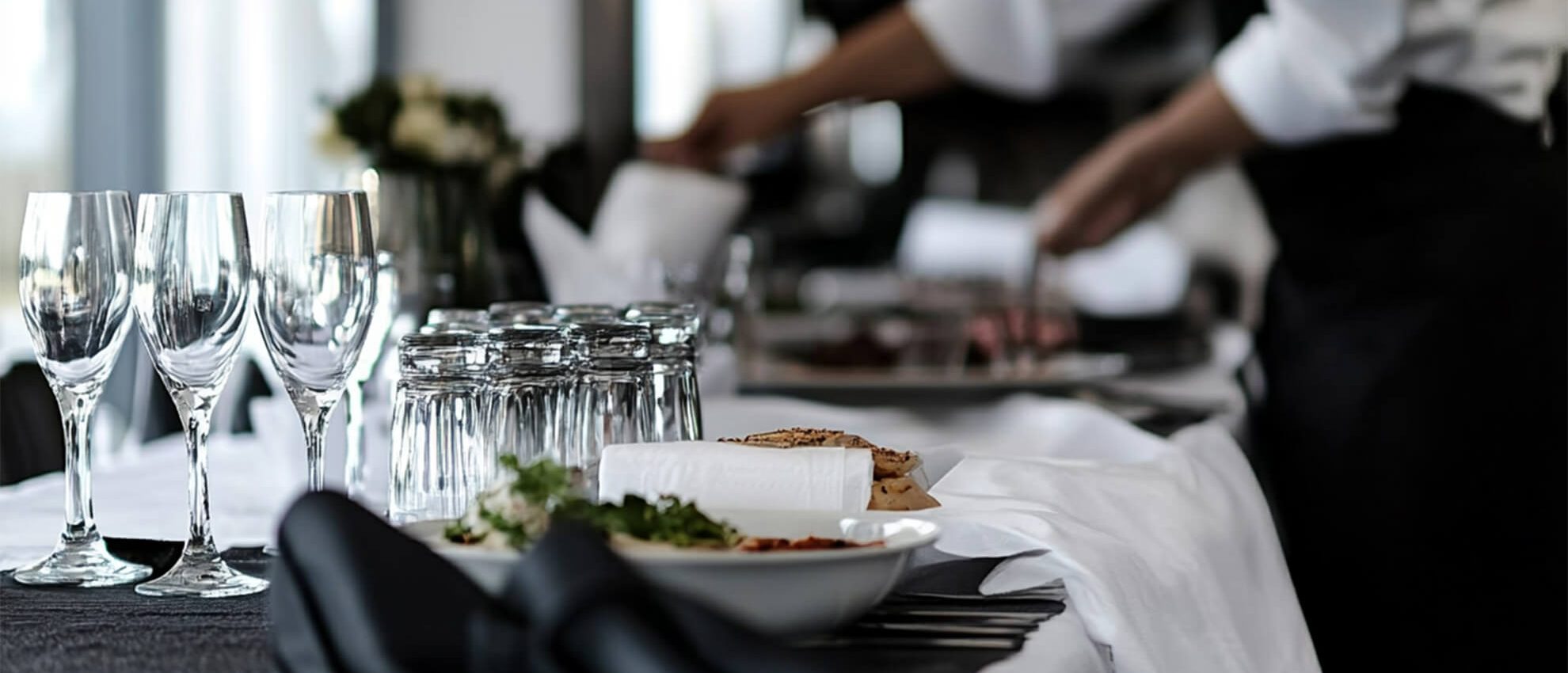 Close-up of an elegant corporate table setting with wine glasses, plates, and formal catering service